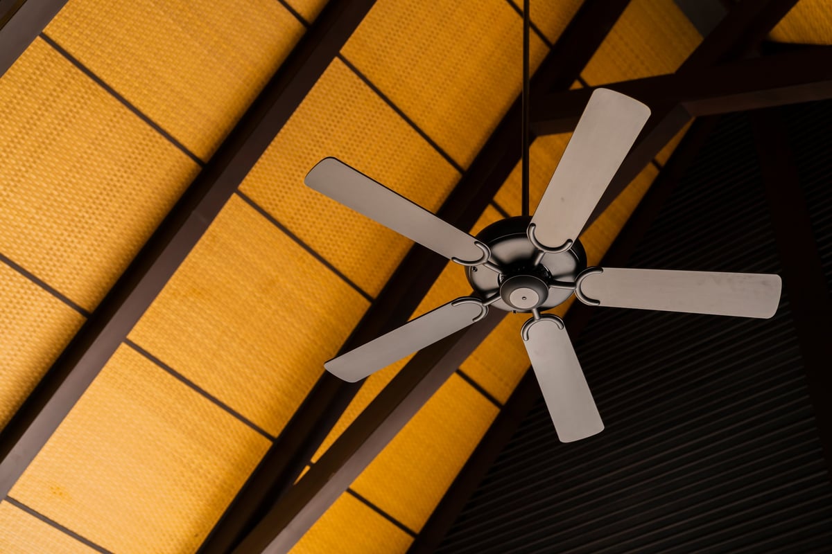 Brown indoor ceiling fan mounted on an exposed wooden ceiling beam