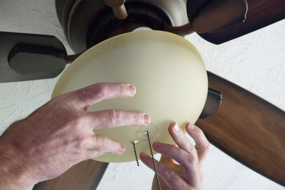 Hands installing the mounting hardware for a ceiling fan