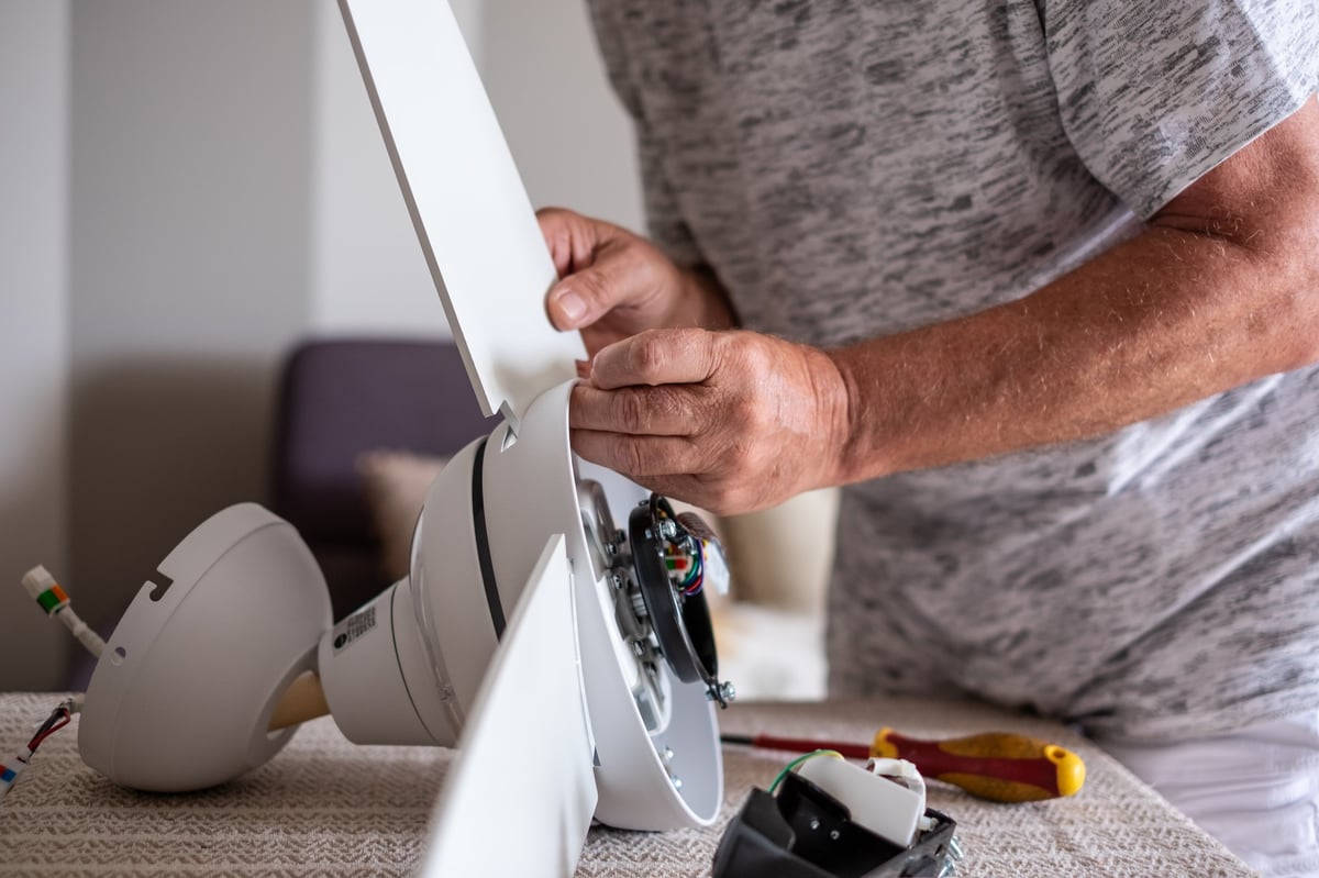 Technician mounting fan blades above a living room