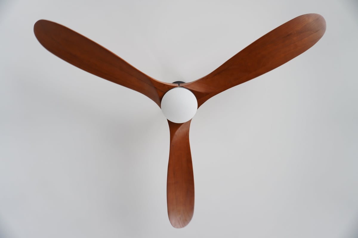 Wood-blade ceiling fan with a central globe light, viewed from below
